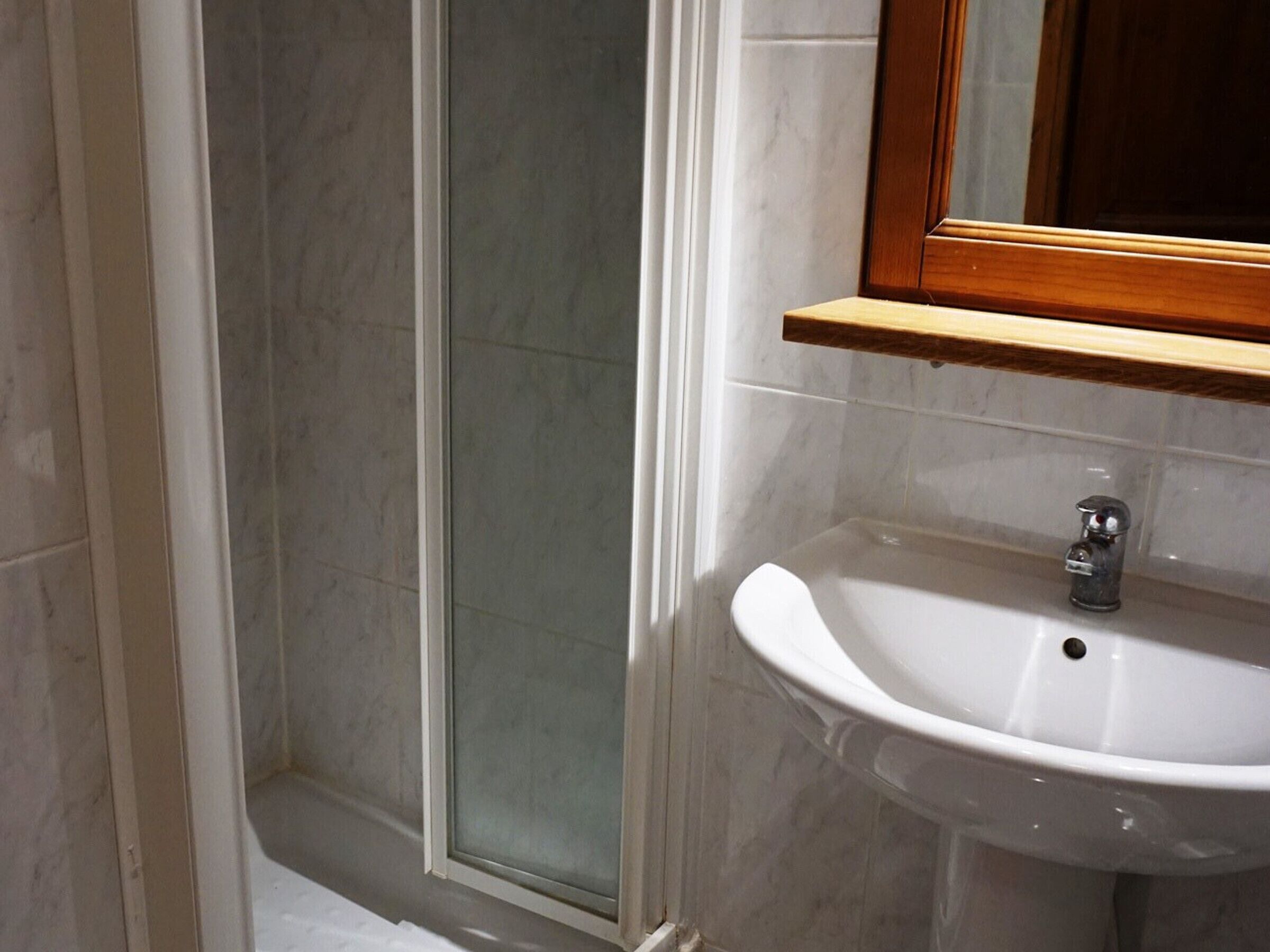 A bathroom with a shower, a sink, and a mirror.