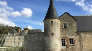 Ein historisches Gebäude mit einem markanten Turm, einer Steinmauer und einem verschlossenen Eingang.