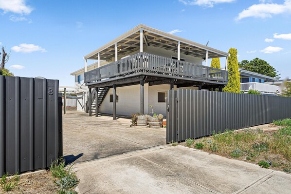 A two-story house with a balcony, a covered patio, and a fenced yard.