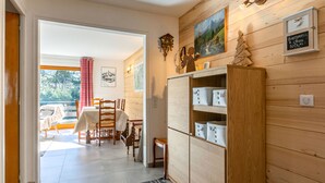 A wooden interior with a dining area, a cabinet with storage boxes, and a painting on the wall.