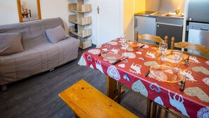 Een gezellige zithoek met een bank, een houten bankje en een eettafel voor twee met een rode tafelkleed.