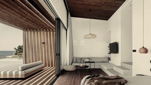 Ein modernes Schlafzimmer mit einem großen Bett, Holzboden, einer Couch und einem an der Wand befestigten Fernseher.