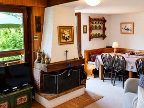 A cozy room with a fireplace, dining table, and chairs. - Comfortable T4, 8 people, 3 bedrooms, Le Grand-Bornand (Le Grand-Bornand)