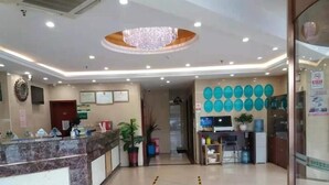 A hotel reception area with a marble counter, a chandelier, framed certificates on the wall, and a row of blue circular decorations. - Greentree Alliance Beijing Daxing District Yizhuang Old Palace Metro Station Hotel (Beijing)