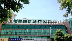 A hotel with a large sign for the GreenTree Alliance Hotel, multiple storefronts below, and parked cars in front. - Greentree Alliance Beijing Daxing District Yizhuang Old Palace Metro Station Hotel (Beijing)