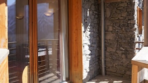Une pièce aux murs en pierre et dotée d’une grande porte-fenêtre coulissante, le tout encadré par une structure en bois.