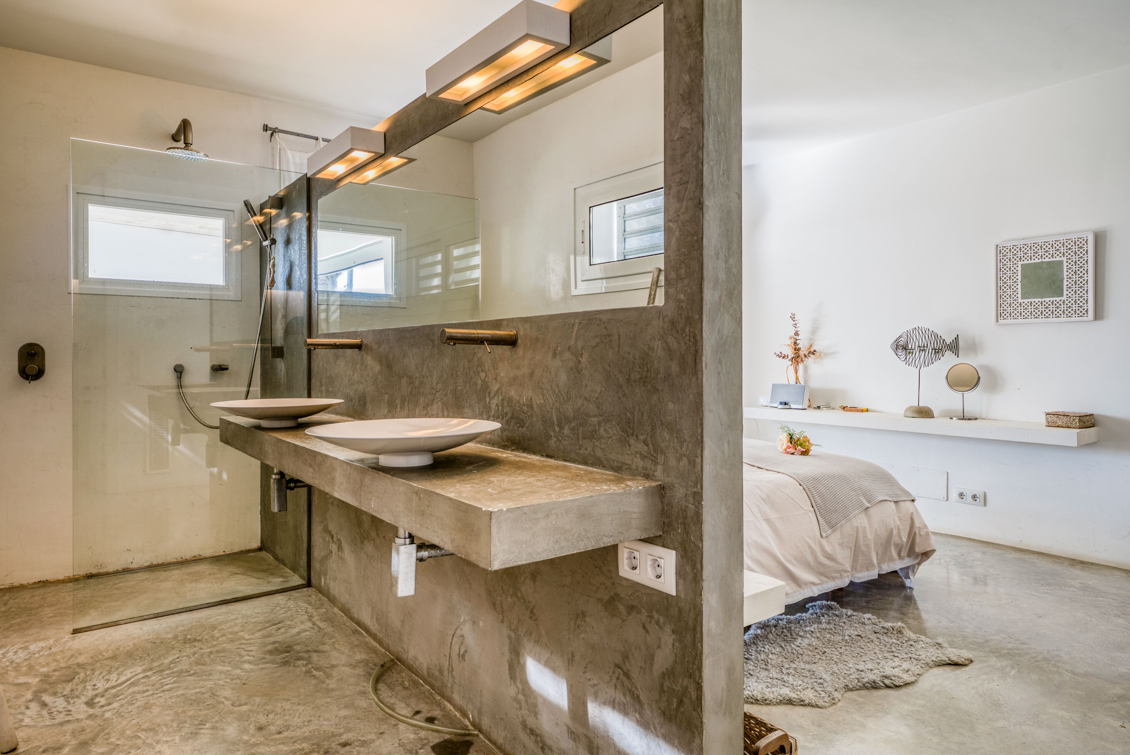 A modern bathroom with a large mirror, two sinks, and a shower.
