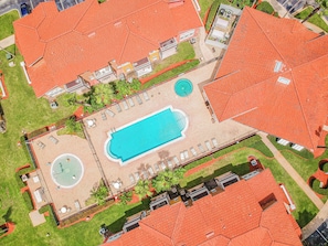 Vista aérea de una propiedad con piscina, zonas de descanso y una fuente circular.