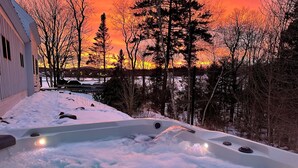 Un jacuzzi con vistas a una puesta de sol y árboles.
