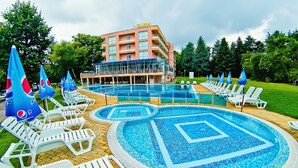A hotel with a swimming pool, lounge chairs, and umbrellas. - Hotel Gloria - All Inclusive (Varna)