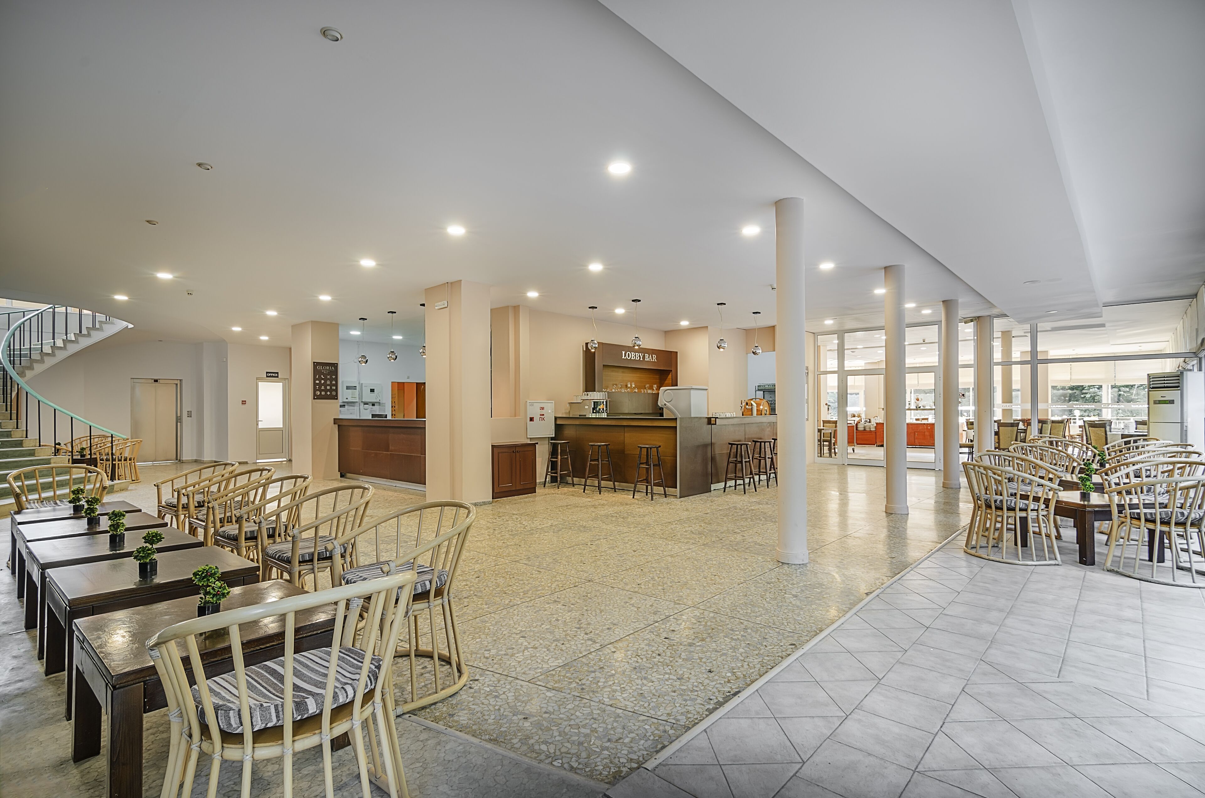 Eine großzügige Hotelhalle mit verschiedenen Sitzbereichen, einer Treppe und einer Bar/Lounge.