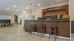 A lobby bar area with a wooden counter, three stools, and overhead lighting. - Hotel Gloria - All Inclusive (Varna)