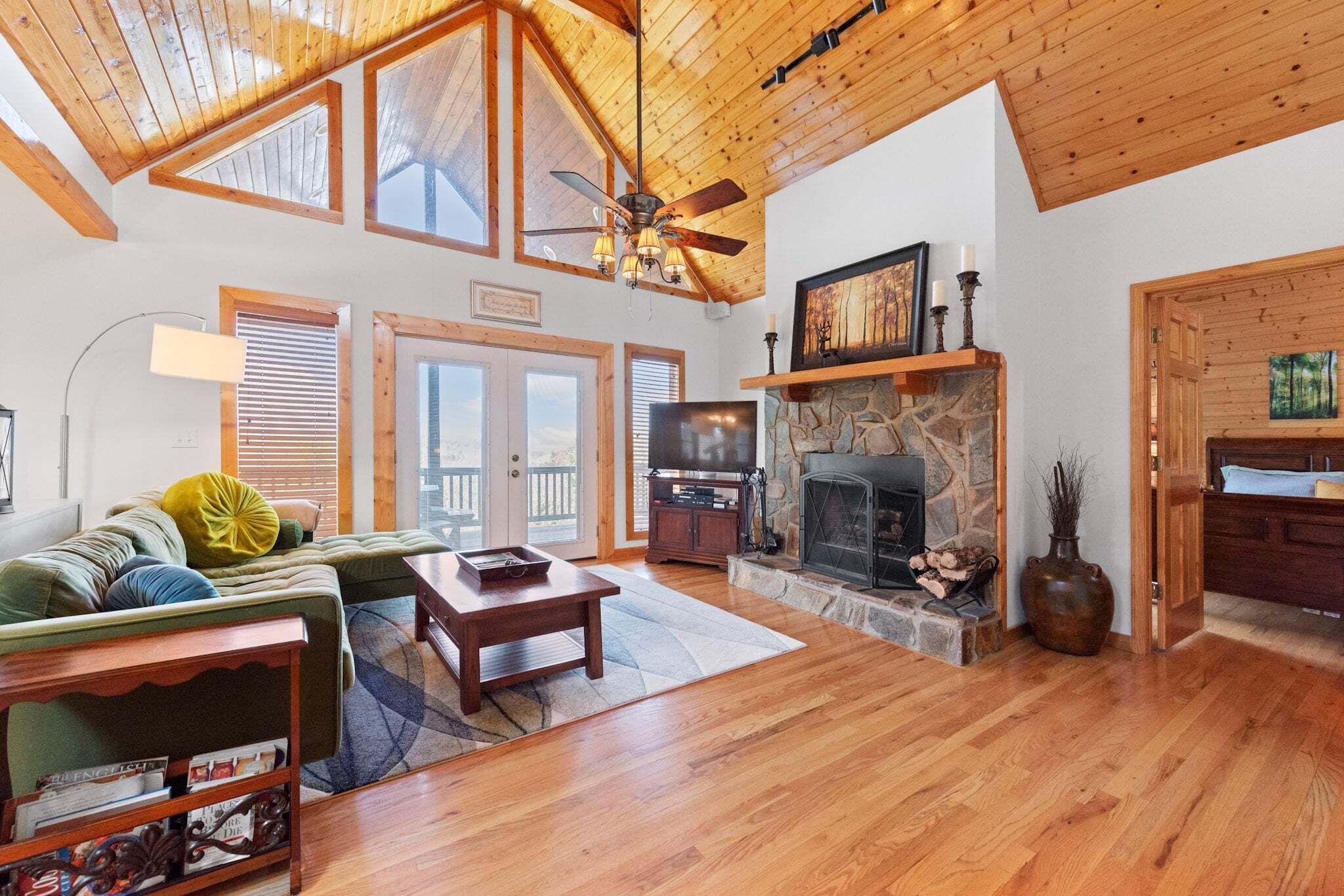 A spacious living room with a fireplace, wooden ceiling, and a television.