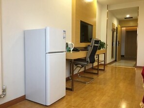 A compact kitchen with a white refrigerator, a wooden dining table, and a black office chair. - Greentree Inn Beijing Yanqing District Badaling Changcheng Kangzhuang Express Hotel (Yanqing)