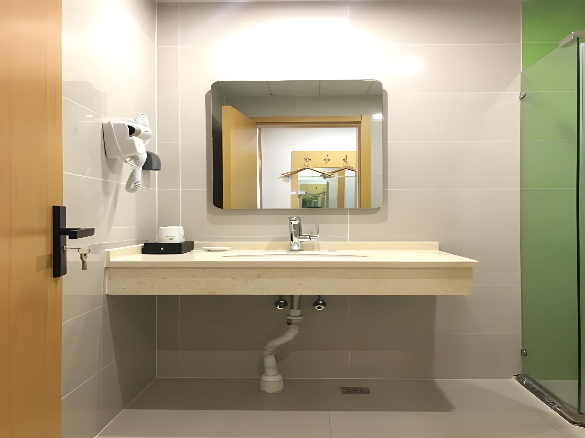 Een moderne badkamer met een wit wastafel, een spiegel en een zeepdispenser.