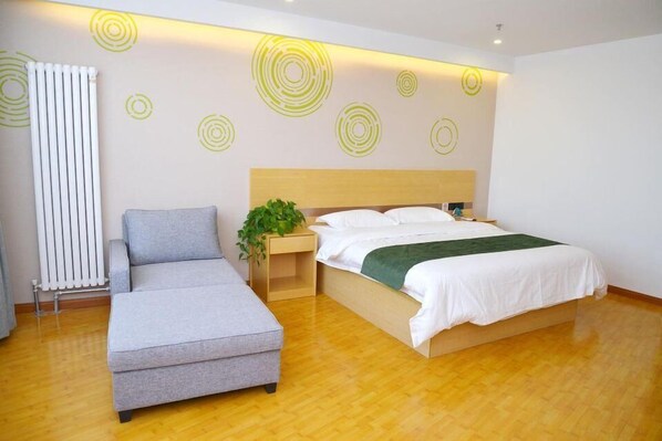 Un dormitorio moderno con una cama, un sofá gris, una mesita de noche de madera con una planta y un radiador.