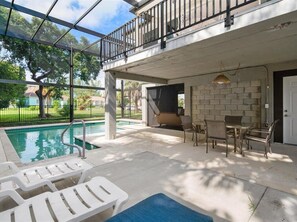 A covered outdoor area with a pool, lounge chairs, and a table with chairs. - 3BR/3BA Marco Island home with heated pool, WiFi, and full kitchen. (Marco Island)