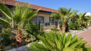 A building with a tiled roof, a balcony with a glass railing, and a garden with various plants and flowers. - Esmeralda Butik Hotel (Manavgat)