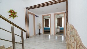 A hotel hallway with a marble floor, a wooden staircase, and a stone accent wall. - Esmeralda Butik Hotel (Manavgat)