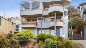 A multi-story residential building with balconies, a staircase, and surrounding vegetation. - Nautica Breath Taking Ocean Views Beachfront (Lorne)