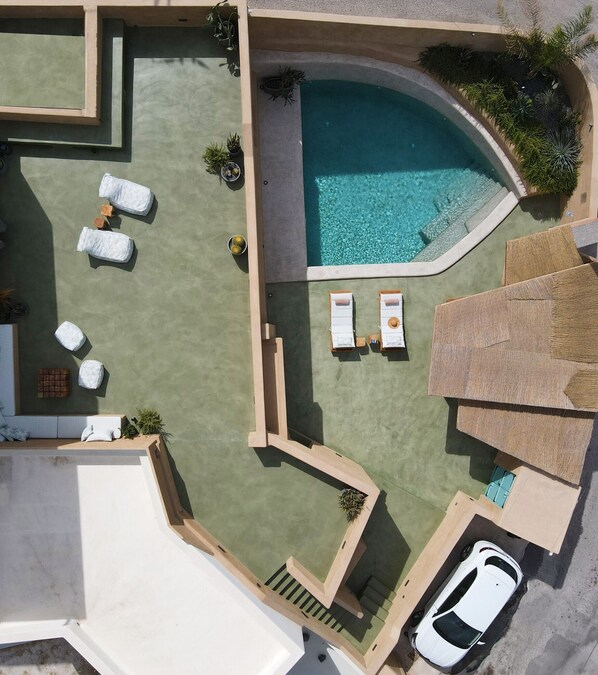 An aerial view of a property with a swimming pool, lounge chairs, a car, and a staircase. - Potamos Luxury House with pool, full privacy (Thira - Santorini)