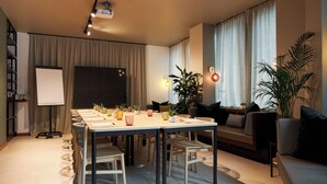A modern living room with a dining area, a projector screen, and a sofa. - Cocoon Salzburg Hauptbahnhof  (Salzburg)