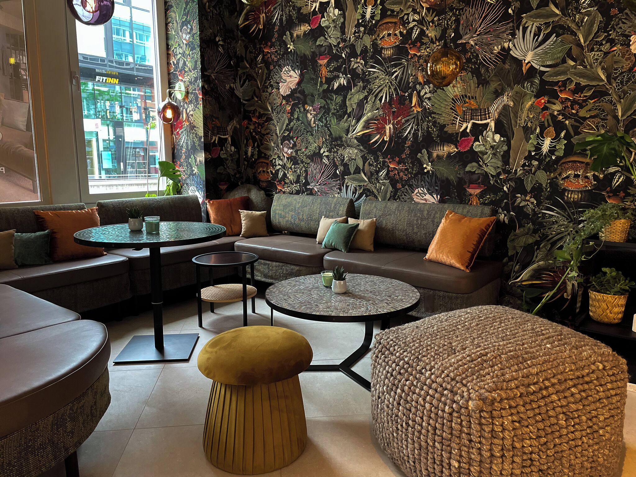 Un interior moderno con un sofá, mesas redondas y un muro decorativo.