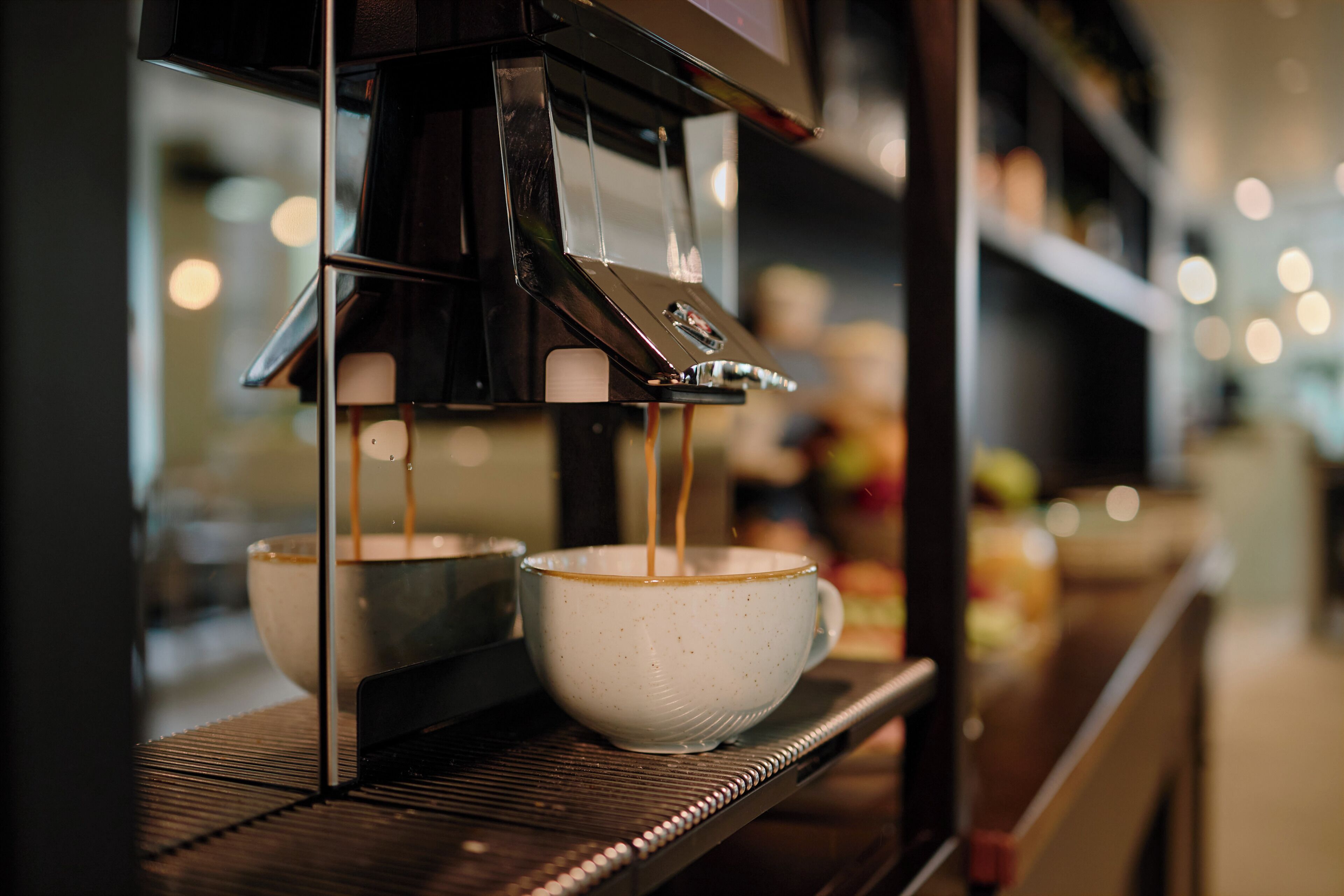 Una màquina de cafè servint cafè en dues tasses sobre un safata metàl·lica.
