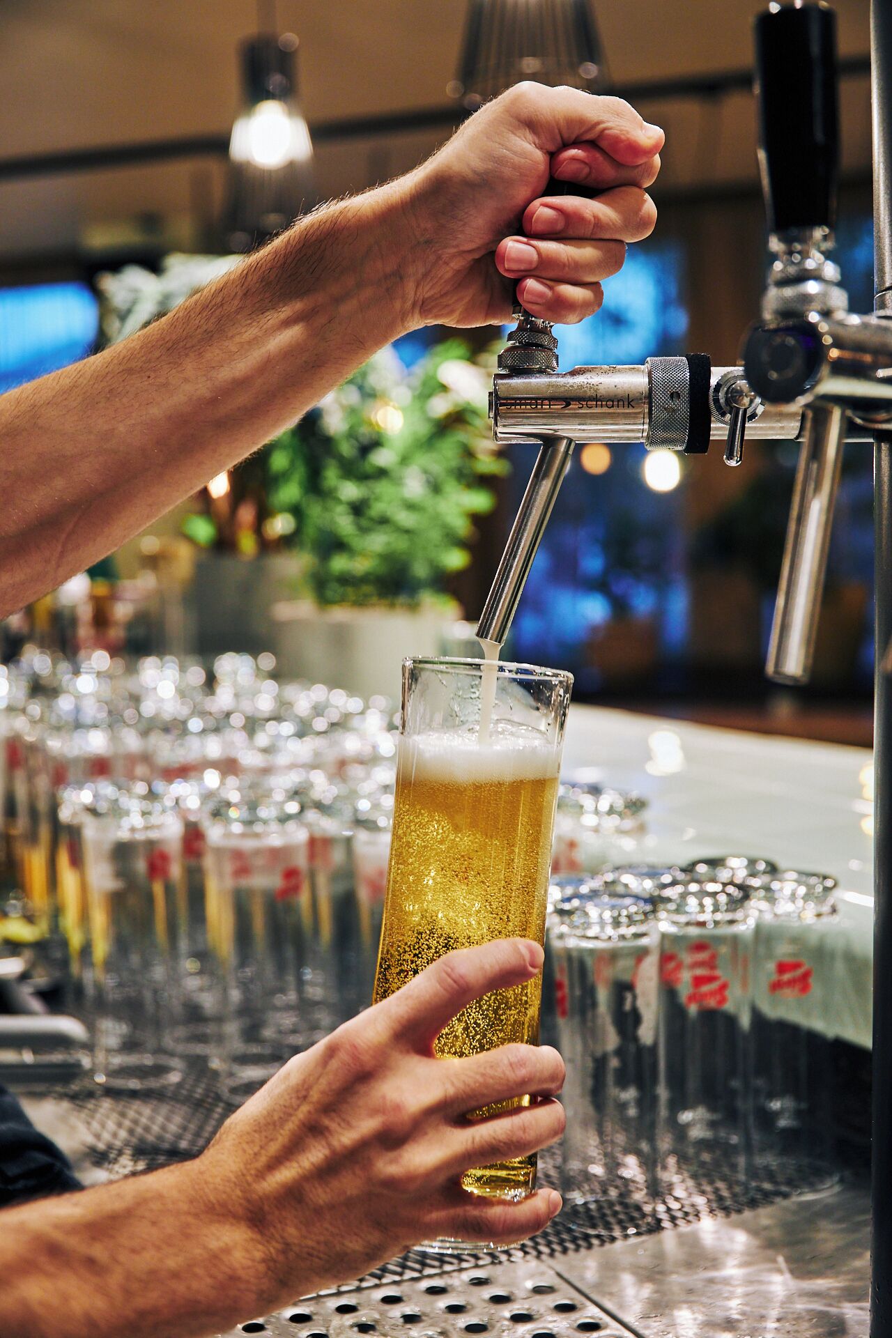 A person pouring beer into a glass at a bar.