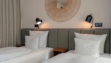 A hotel room with two beds, a round mirror, and two bedside lamps.