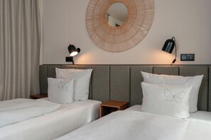 Una habitación de hotel con dos camas, un espejo redondo y dos lámparas de noche.