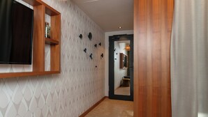 A hallway with a wooden floor, a mounted television, and a patterned wall. - Cocoon Salzburg Hauptbahnhof  (Salzburg)