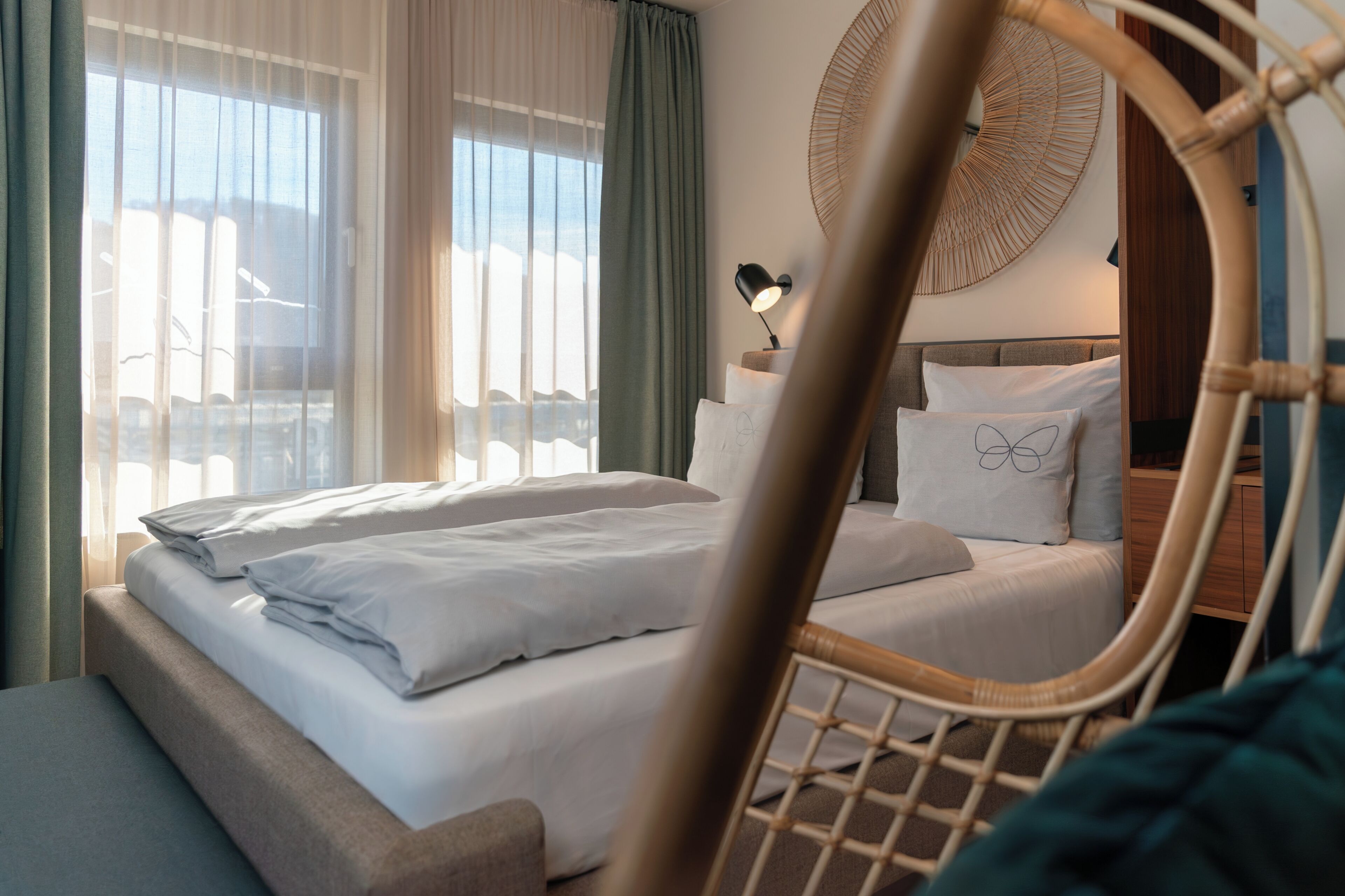 Een hotelkamer met een bed, een stoel en een wandlamp.