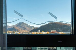 Vista a través de una ventana con montañas y edificios al fondo.