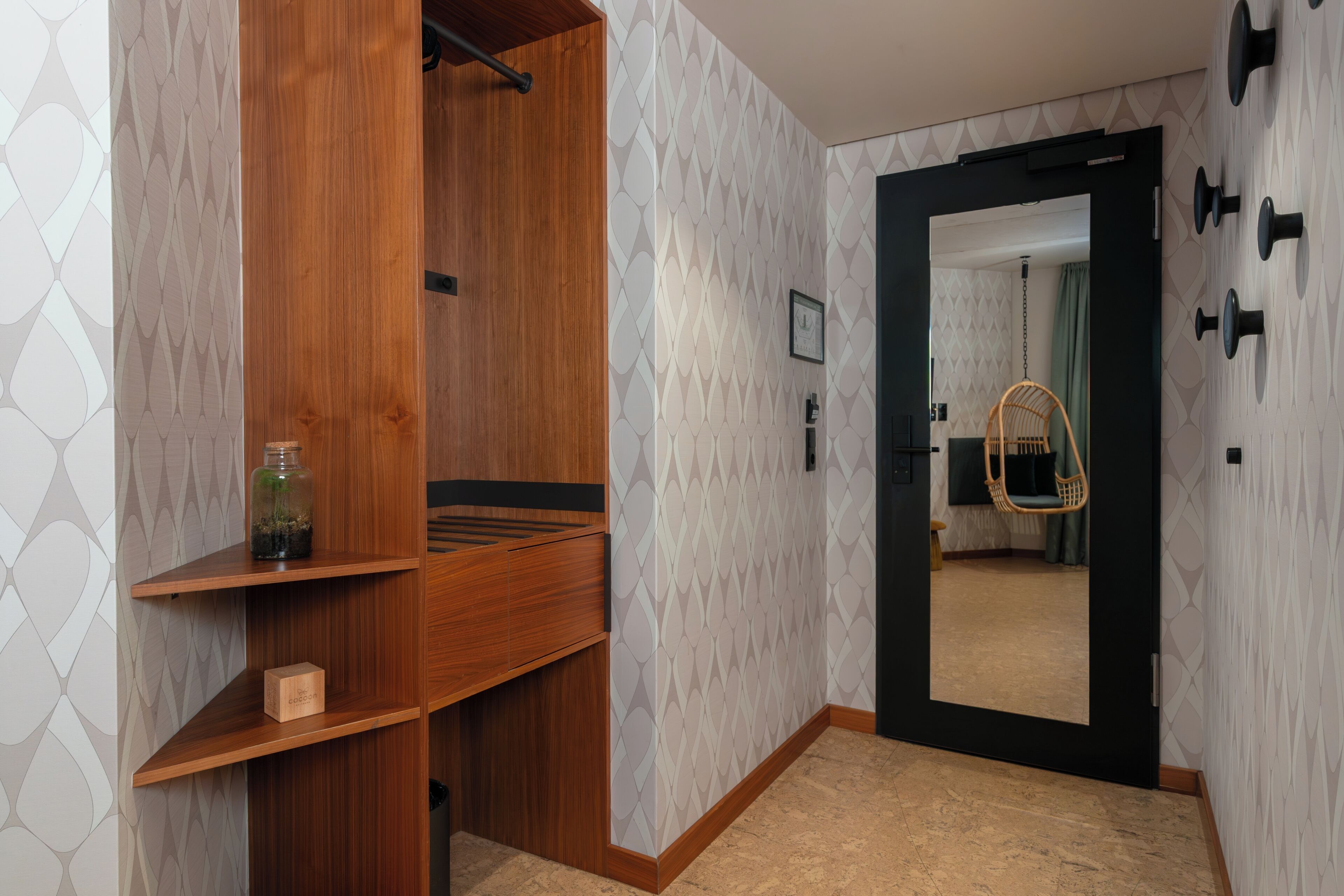 Habitación de hotel con armario de madera, un espejo y un sillón colgante.