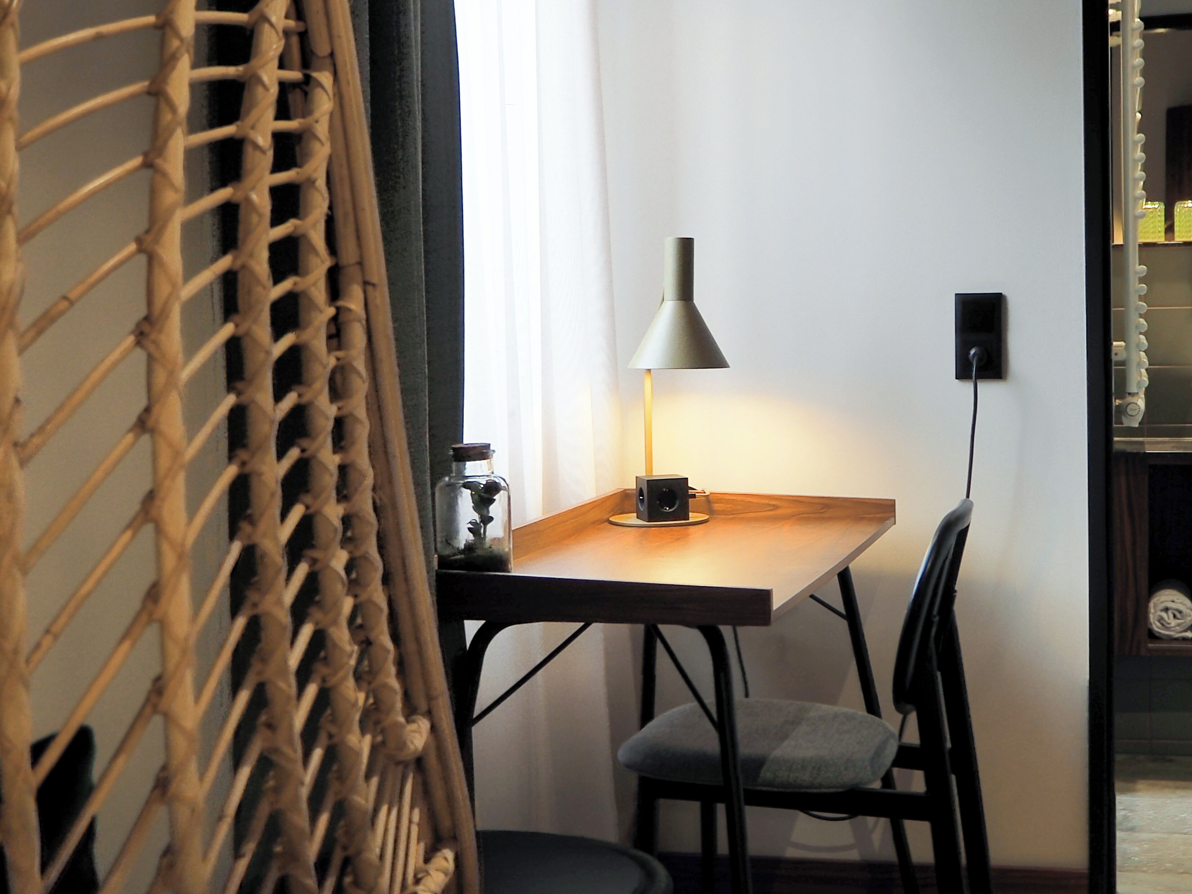 Une pièce comprenant une table en bois, une lampe, une chaise et un petit objet décoratif posé sur la table.