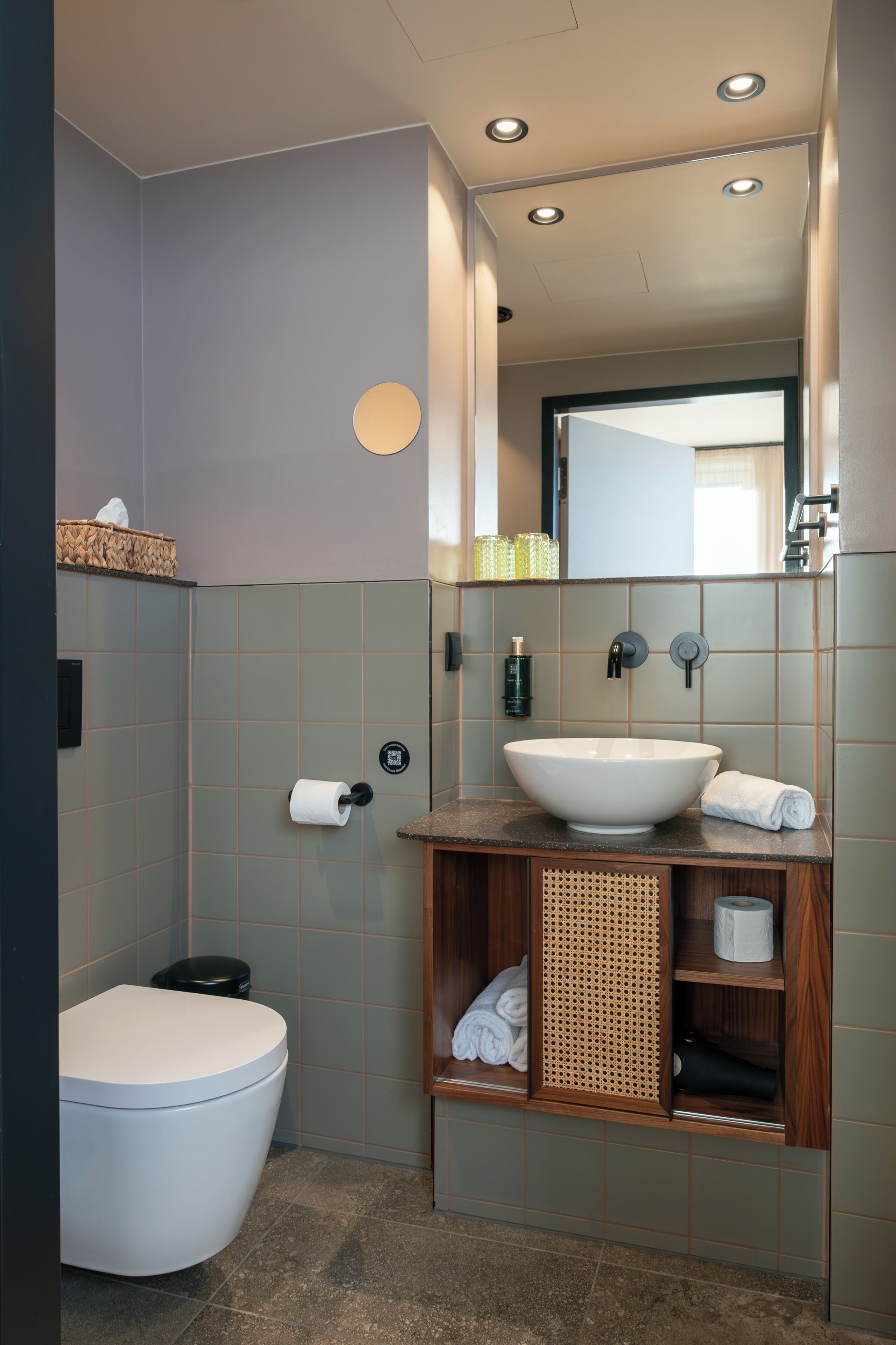 Ein modernes Badezimmer mit Toilette, Waschbecken und Spiegel.