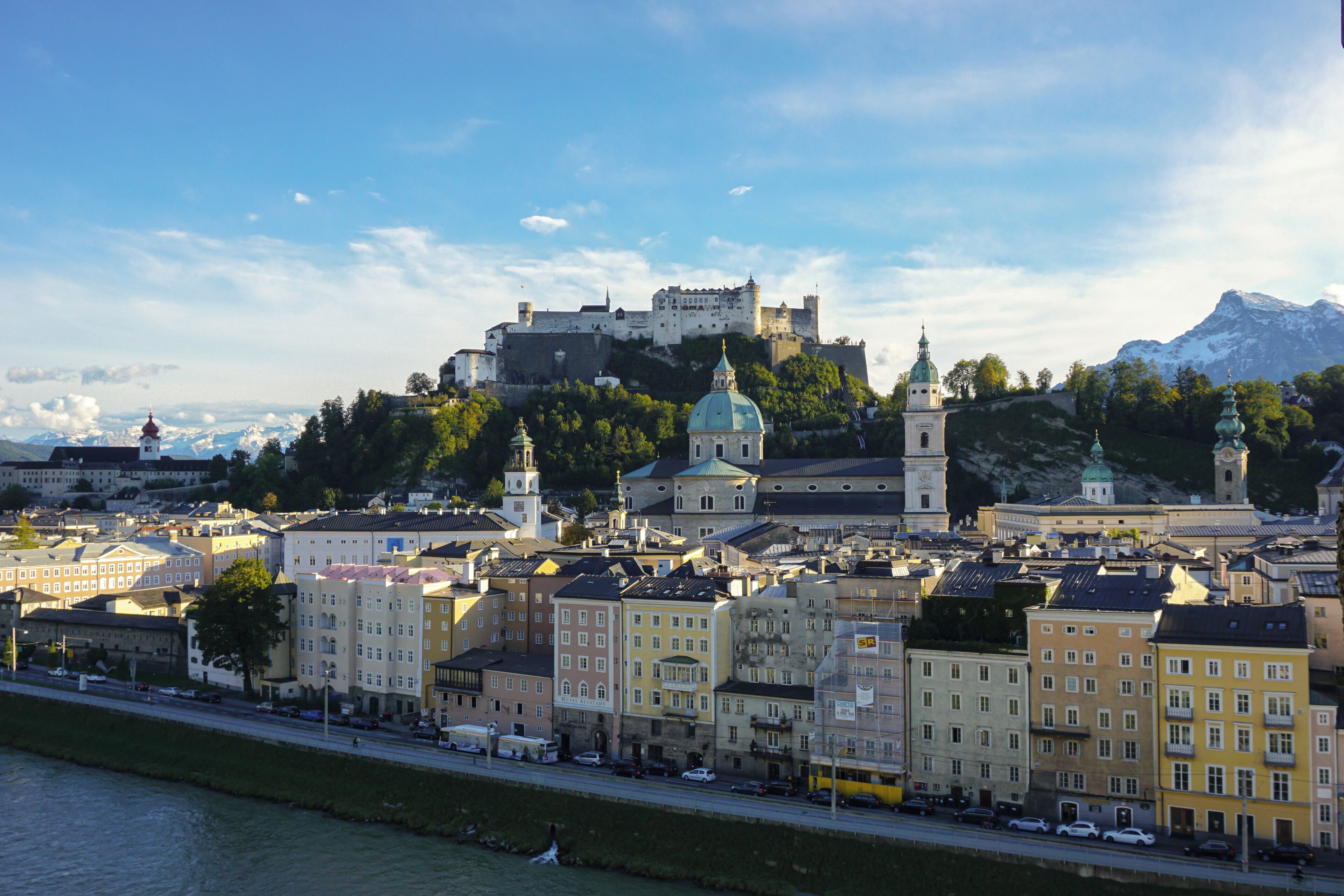 A historic cityscape with a prominent castle on a hill, surrounded by a river and a variety of buildings.