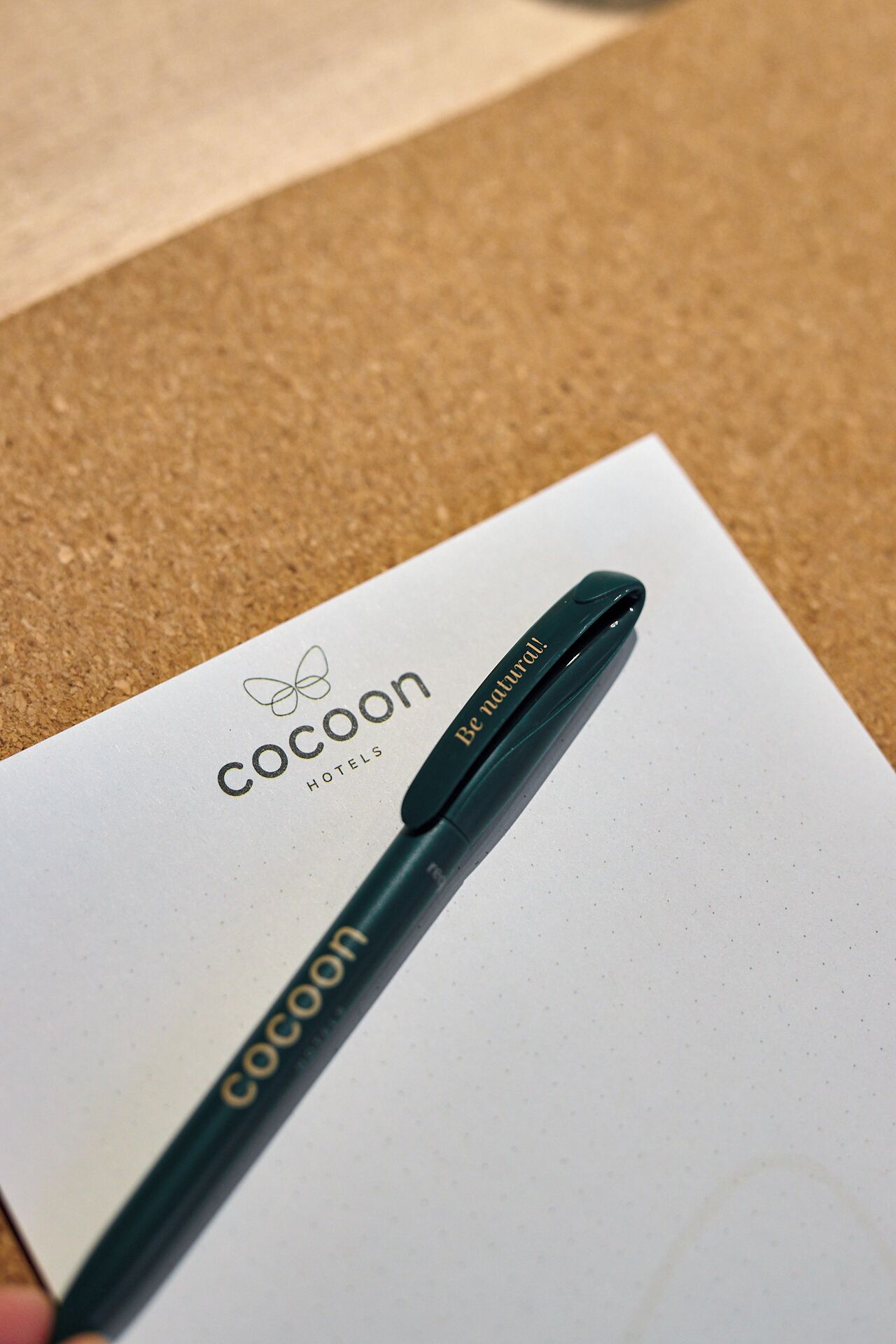 A pen with the brand name 'Cocoon' and the slogan 'Be natural!' on a white paper with the same brand name and logo.
