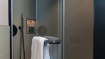 A modern shower enclosure with a glass door, a handheld showerhead, and a towel rack.