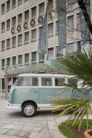 Una furgoneta antigua estacionada frente a un edificio con rótulos que dicen 'cocoon'.