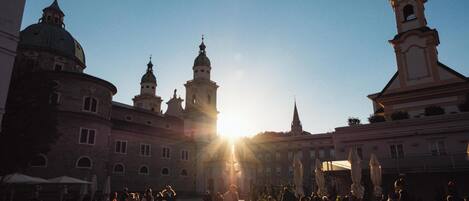 A historical building with multiple domes and towers, a central open space, and people walking around.