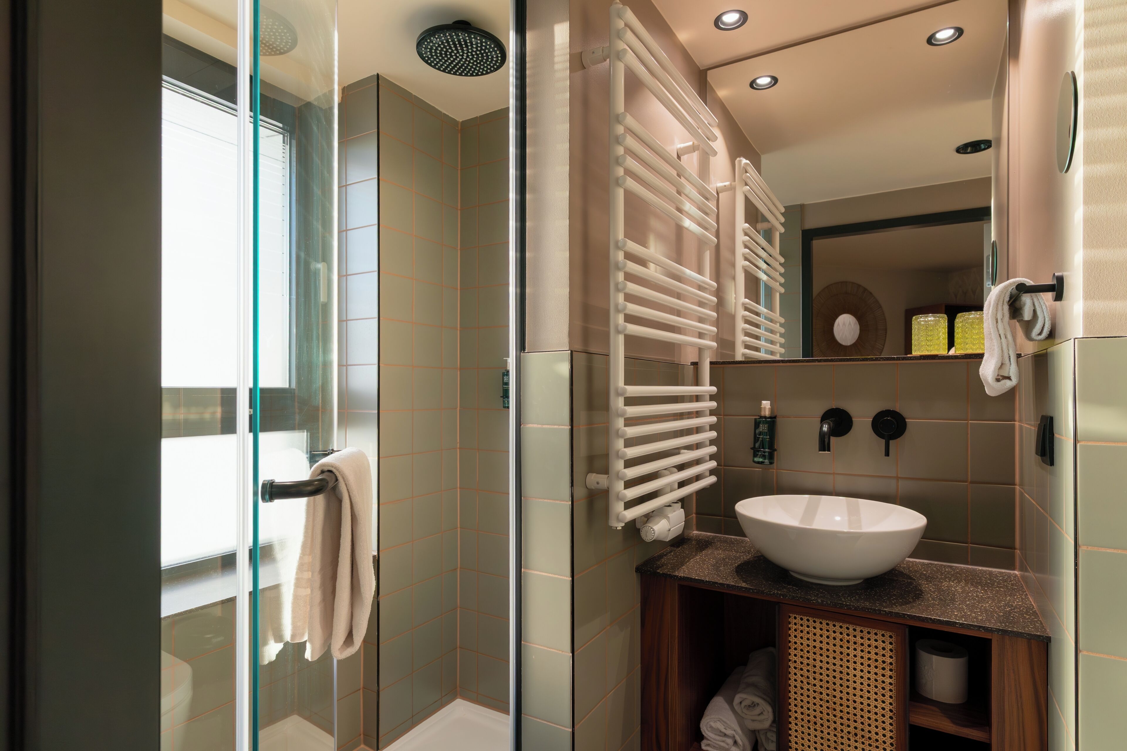 A modern bathroom with a glass shower enclosure, a white sink, and a wooden vanity.