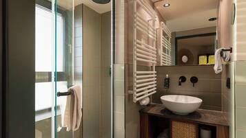 A modern bathroom with a glass shower enclosure, a white sink, and a wooden vanity.