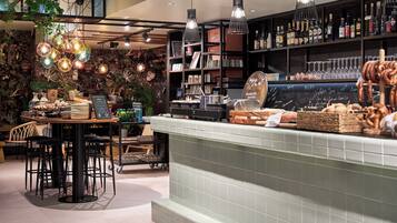 A bar area with a counter displaying snacks and drinks, shelves with bottles, and hanging light fixtures.