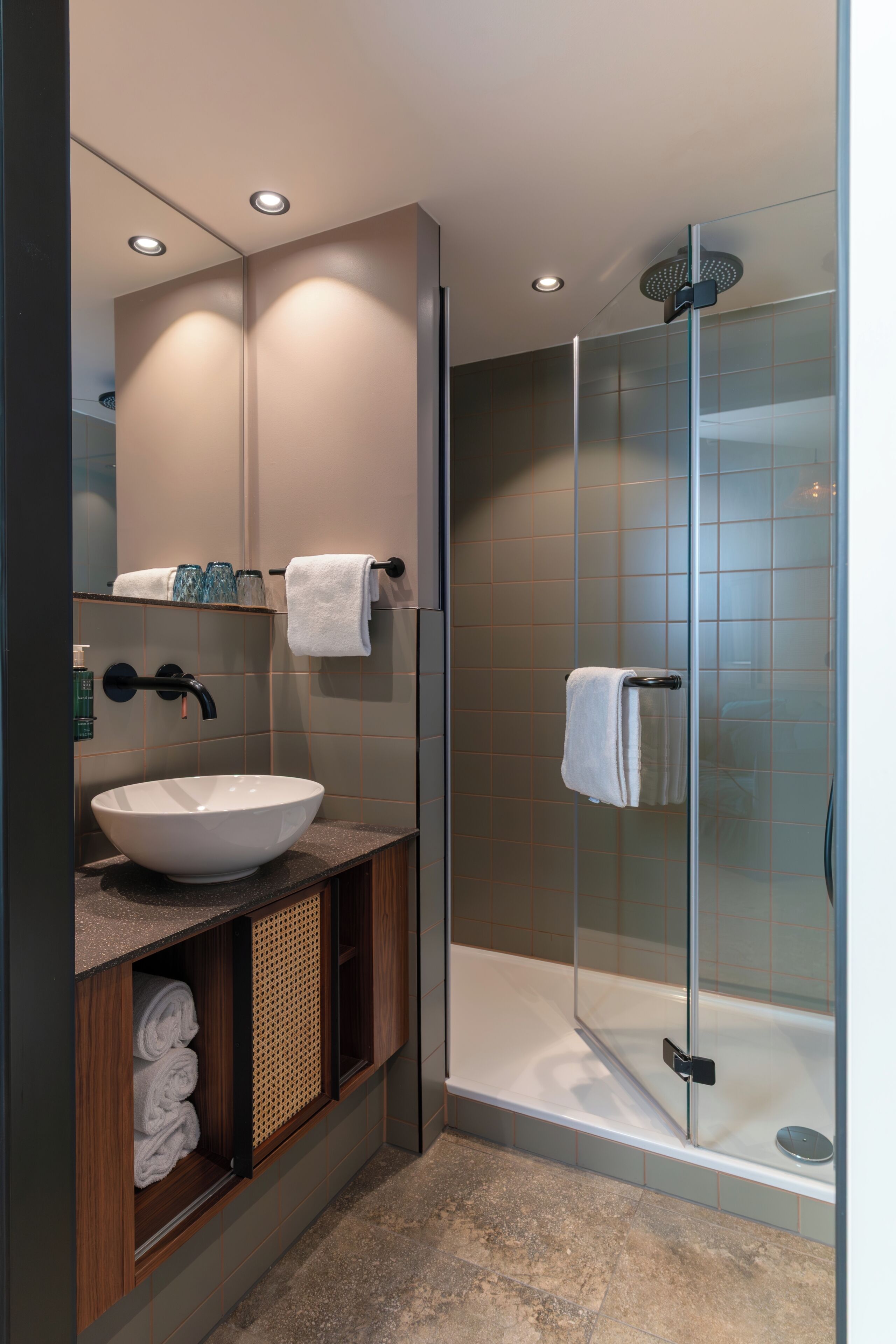 A modern bathroom with a glass-enclosed shower, a white sink, and a mirror above the sink.