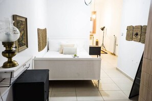 A bedroom with a bed, bedside table, lamp, and a small desk with a chair. - Urban Orange by Domisi with private Jacuzzi (Ρέθυμνο)