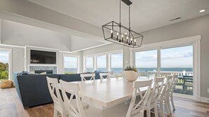 Een ruime keuken met een groot eiland, witte kasten en uitzicht op de oceaan.