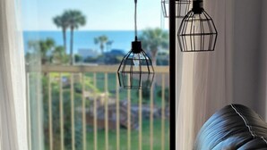 A leather sofa with a pillow that reads "BEACH" and a view of the outdoors through a window. - New Heated Pool & Hot tub! Views plus 2 recliners! (Galveston)