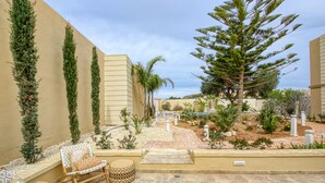 A patio area with outdoor seating, a pathway, and a variety of plants and trees. - Ta’ Benna Villa Gozo Luxury Accommodation (Ghajnsielem)
